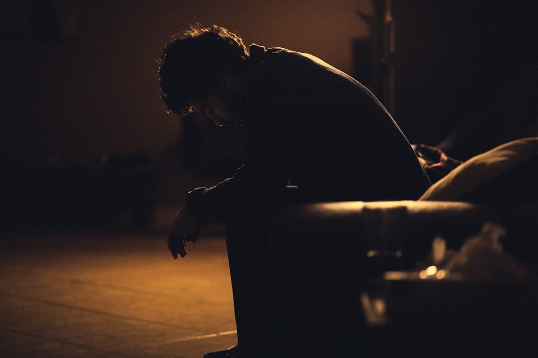 man in black shirt sitting on chair looking depressed